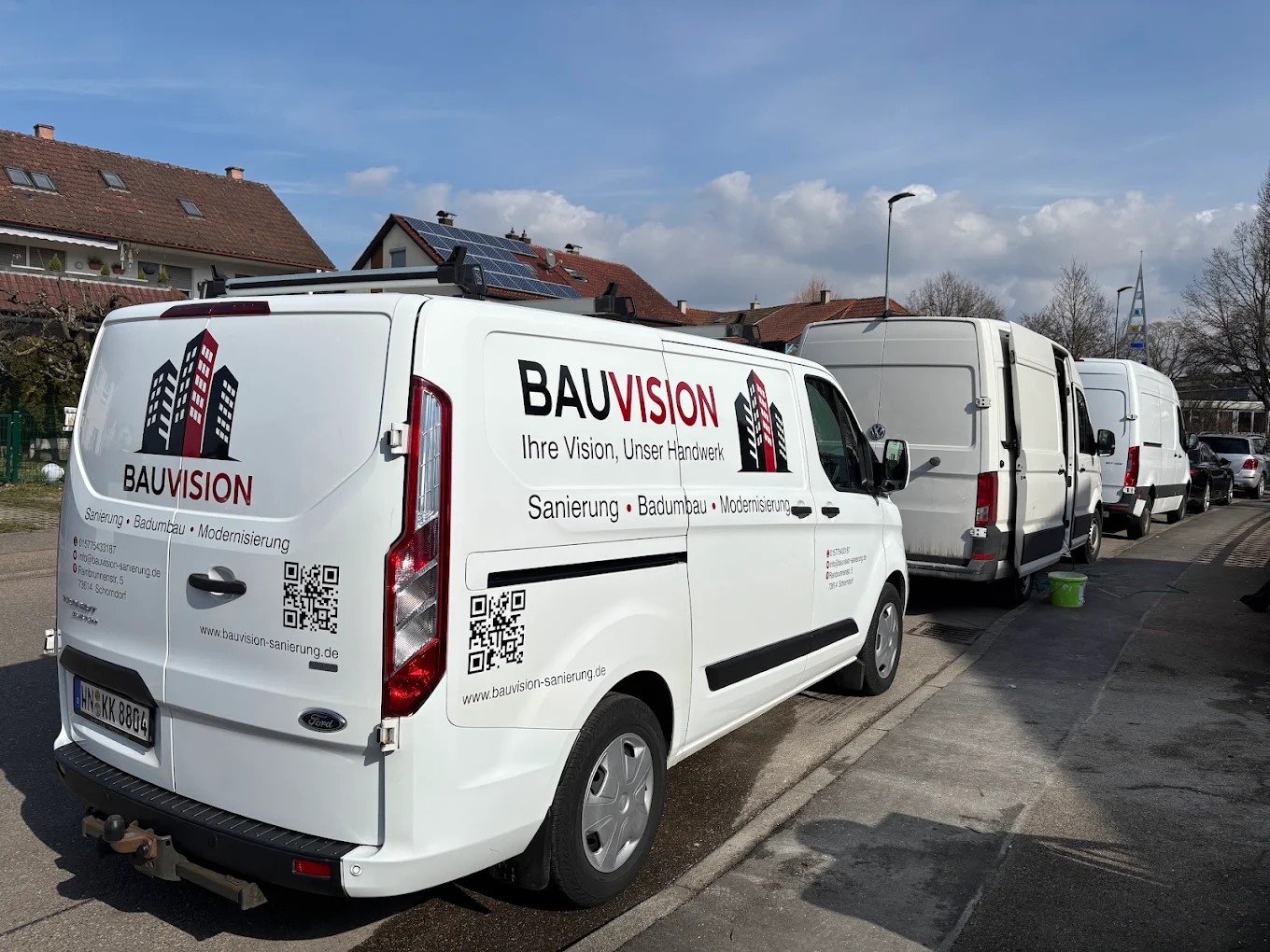 Beschriftete BAUVISION Firmenfahrzeuge vor einer Baustelle